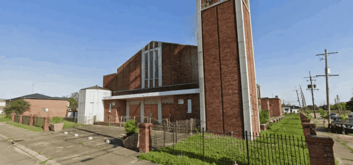 A brick church building with a tall tower under a clear blue sky.